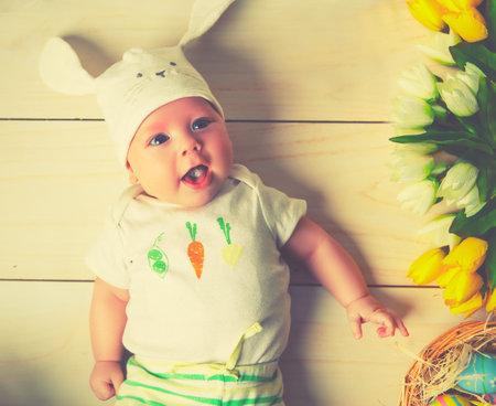 happy baby child with Easter bunny ears  and flowers