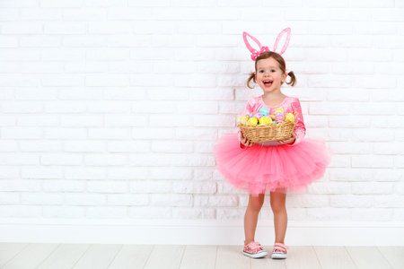 Happy child girl in a costume Easter bunny rabbit with ears and a basket of eggs