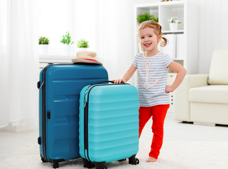 happy child girl tourist packs clothes into a suitcase for travel, vacationの写真素材