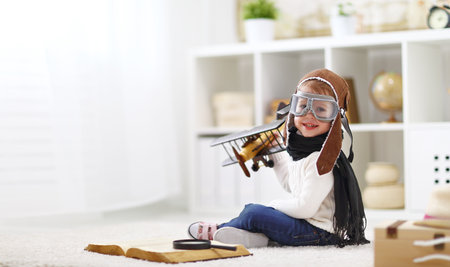concept of children's dreams and travels.  pilot aviator child with a toy airplane plays at home in his roomの写真素材