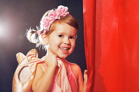 little child girl ballerina ballet dancer on the stage in red side scenesの写真素材