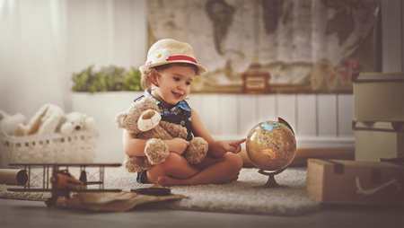 Concept travel. child girl at home dreaming of travel and tourism, exploring the world map and globeの写真素材