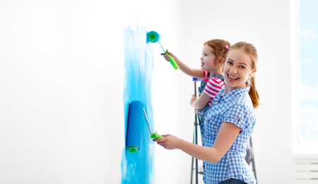 happy family mother and child daughter making repairs, paint the wall at homeの写真素材