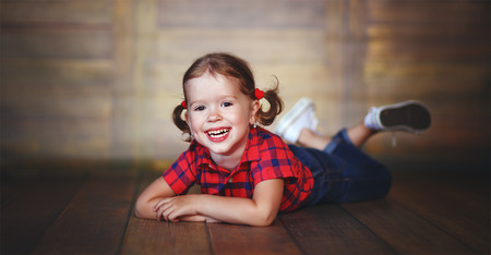 happy child little girl laughing at empty wooden wallの写真素材