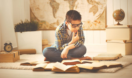 A boy teenager studying, reading books, preparing for exams at homeの写真素材