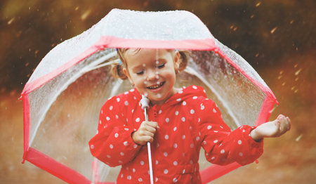 happy child girl laughing with an umbrella in the rain