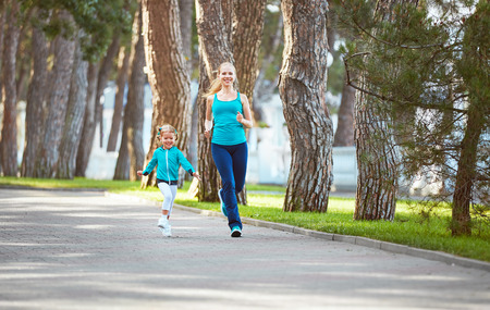 sports family mother and child daughter are engaged in running and athletics in the summer in the parkの写真素材
