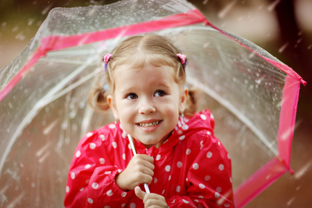 happy child girl laughing with an umbrella in the rainの写真素材