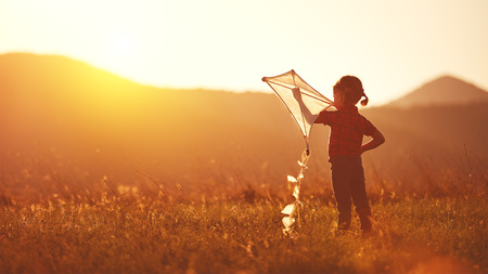 happy child girl with a kite on meadow in summer in natureの写真素材