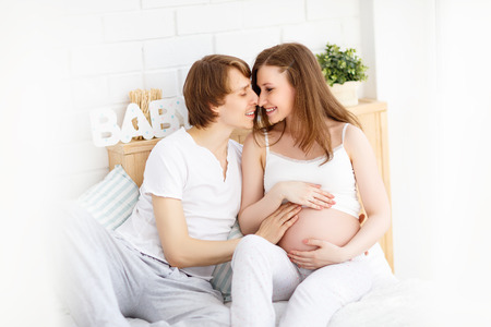 Happy future parents, dad and a pregnant mother in anticipation of baby at homeの写真素材