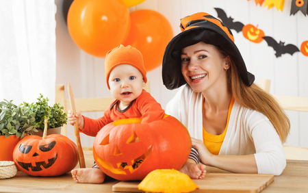 family mother and baby son are preparing for Halloween carve a pumpkin and decorate the houseの写真素材