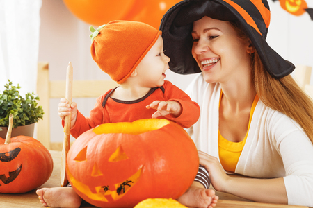 family mother and baby son are preparing for Halloween carve a pumpkin and decorate the houseの写真素材