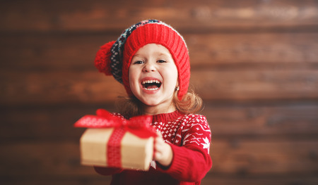 happy child girl with a Christmas present on wooden backgroundの写真素材