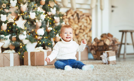Happy baby by a Christmas tree with giftsの写真素材