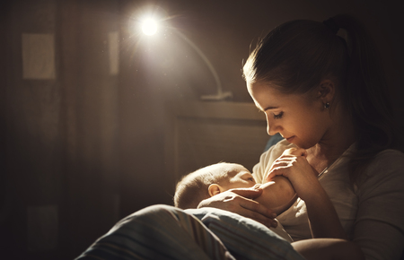 breastfeeding. mother feeding a baby breast in bed dark nightの写真素材
