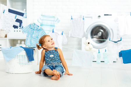  child fun happy little girl  to wash clothes and laughs in the laundry roomの写真素材