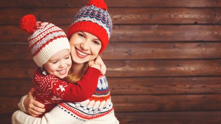  happy family mother and child girl with christmas hat hugs at wooden  backgroundの写真素材