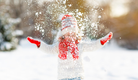 happy child girl throws up snow on a winter walk