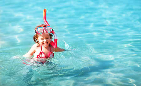 Happy child girl in a mask on the beach in summerの写真素材