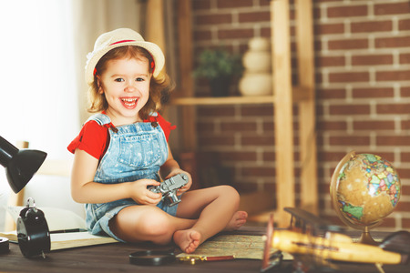 Happy child girl preparing to travel with a card and photo cameraの写真素材
