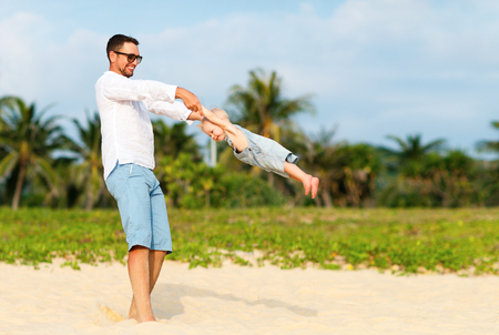 happy family father turns baby son on the beachの写真素材
