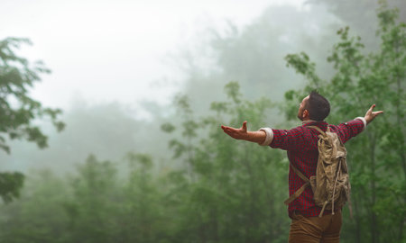 Male tourist on top of gray mountain in fog in autumnの写真素材