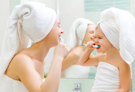 Mother and child daughter brush their teeth with a toothbrush in the bathroomの写真素材