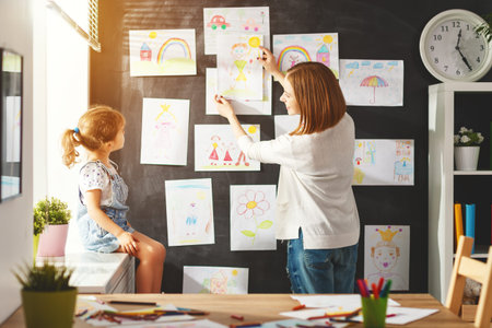 Mother and child girl hang their drawings on the wallの写真素材