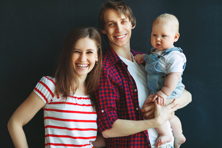 Happy family father mother and baby son on a black backgroundの写真素材