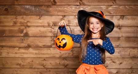 Laughing funny child girl in a witch costume in halloween