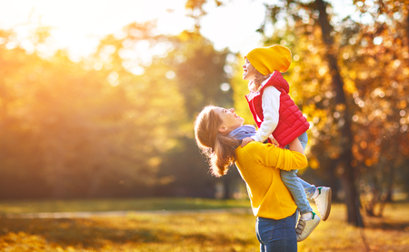happy family mother and child daughter playing and laughing on   autumn walkの写真素材