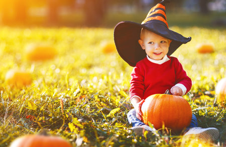 happy baby boy with pumpkin outdoors in halloweenの写真素材