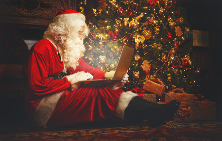 Santa Claus with a computer before christmasの写真素材