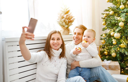 happy family   photographed on phone, makes selfies in  Christmas morning at tree
の写真素材