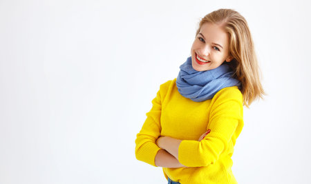 happy young woman in a yellow sweater on a white backgroundの写真素材