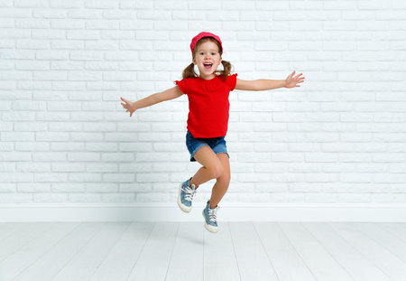 happy funny child girl jumping around empty wallの写真素材