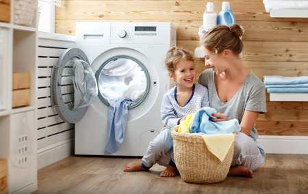 Happy family mother housewife and child daughter in laundry with washing machine 
の写真素材