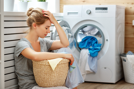 tired  housewife woman in stress sleeps in laundry room with washing machine  の写真素材