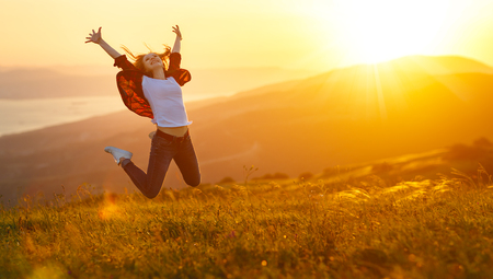 Happy woman jumping and enjoying life in field at sunset in mountains
の写真素材