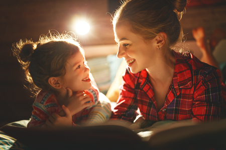 mother and child daughter reading book in bed before going to sleep 
の写真素材