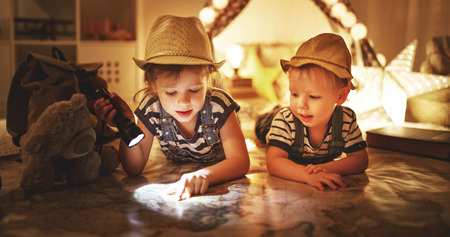 funny happy children tourist with flashlight and world map and backpack  の写真素材