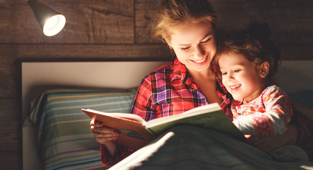 mother and child daughter reading book in bed before going to sleep 
の写真素材