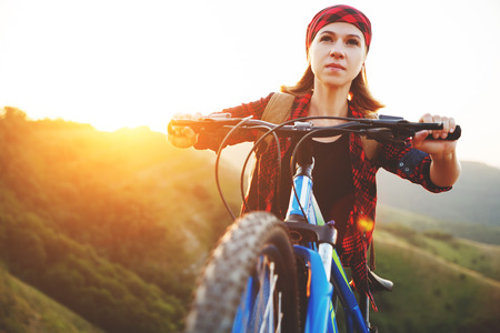 Woman tourist on a bicycle at the top of the mountain at sunset outdoors during a hike in summer
の写真素材