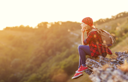 Woman tourist at the top of the mountain at sunset outdoors during a hike in summerの写真素材