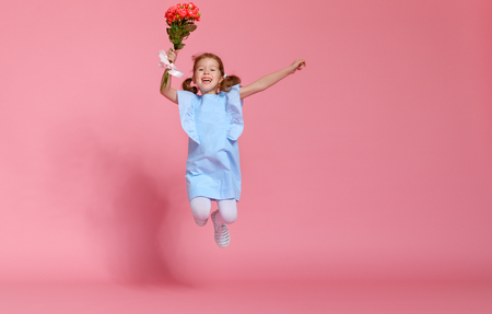 funny child girl runs and jumps with bouquet of flowers on a colored background
の写真素材