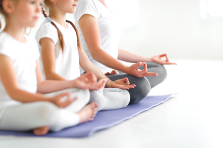 children practicing yoga in a lotus pose with a teacherの写真素材