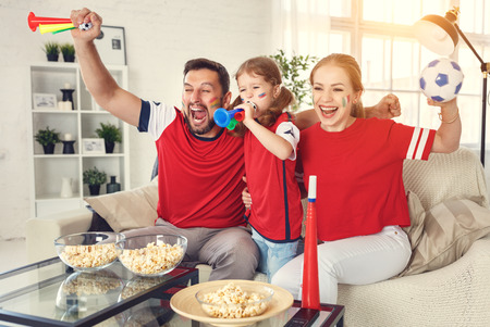 A family of fans watching a football match on TV at home
の写真素材