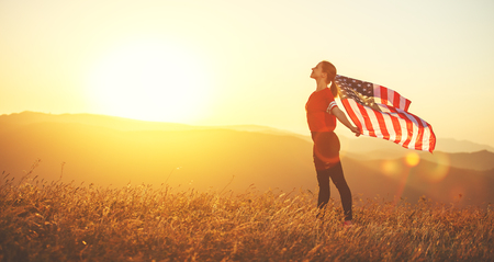 young happy woman with flag of united states enjoying the sunset on natureの写真素材