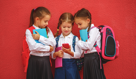 Happy children girls girlfriends schoolgirls student elementary school with a smartphoneの写真素材