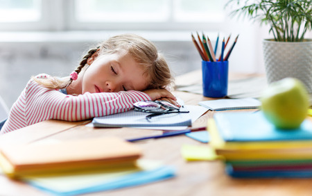 tired child girl fell asleep when she did her homework, studied writing and reading  at homeの写真素材